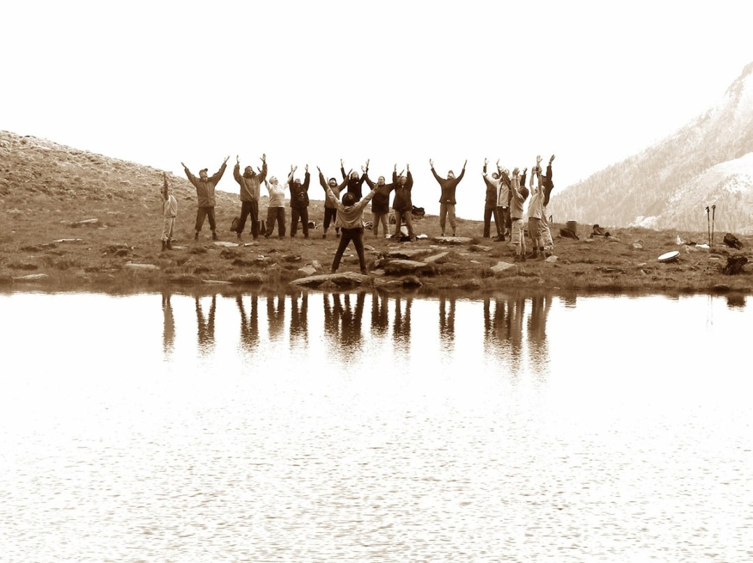 sepia image of a group of people raising their hands by a lake