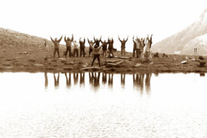 sepia image of a group of people raising their hands by a lake